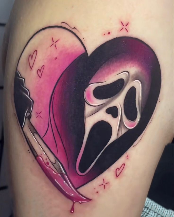 a heart shaped tattoo with a knife and mask on it's back side thigh