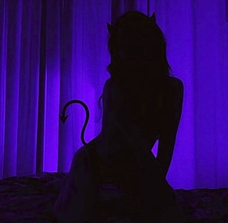 a woman is sitting on a bed in the dark with her cat ears hanging down