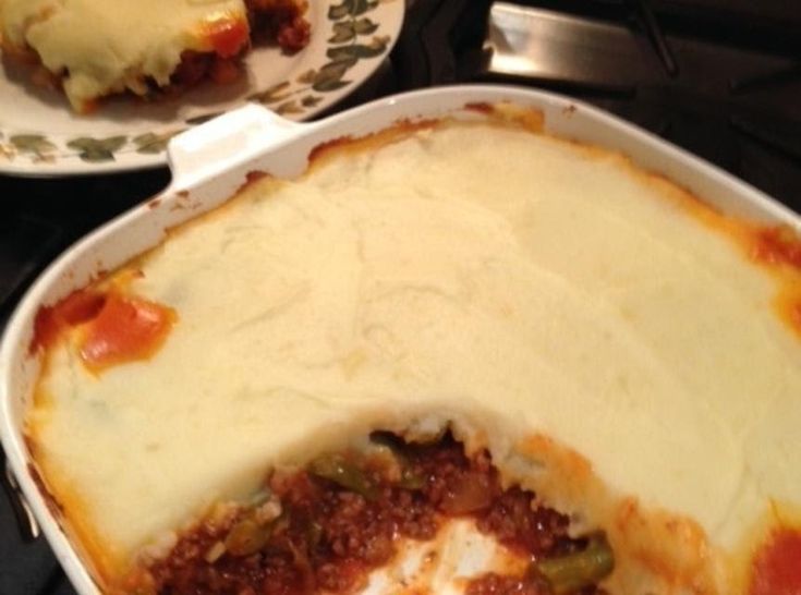 a casserole dish with meat and cheese in it sitting on a stove top