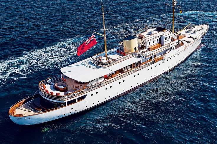 an aerial view of a large white boat in the ocean with a red flag on it's mast