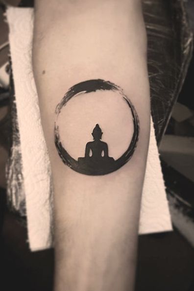 a person with a tattoo on their arm sitting in the middle of a circular shape