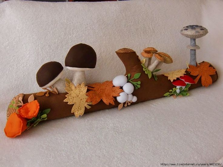 a stuffed animal is sitting on top of a wooden log with leaves and mushrooms around it