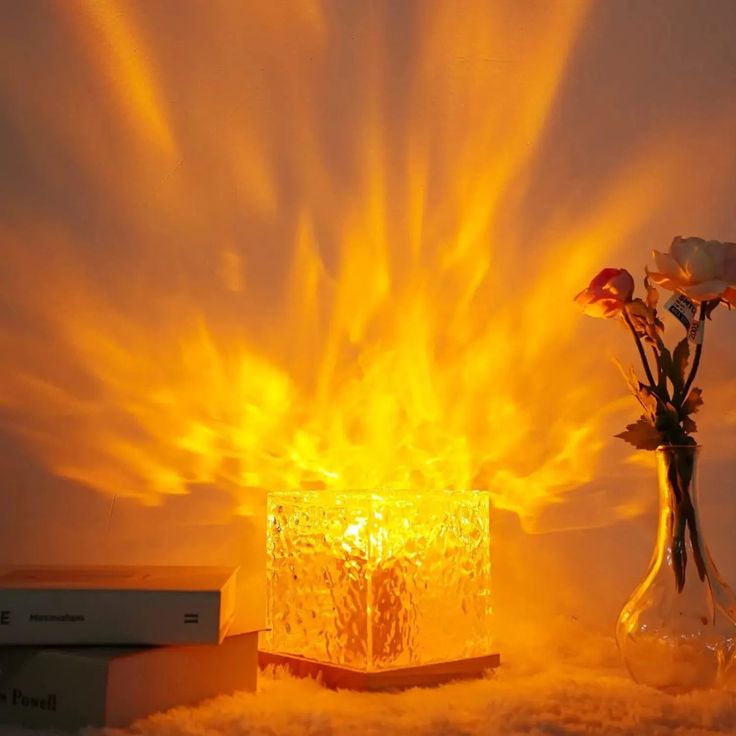 a vase filled with flowers sitting on top of a table next to a book and lamp