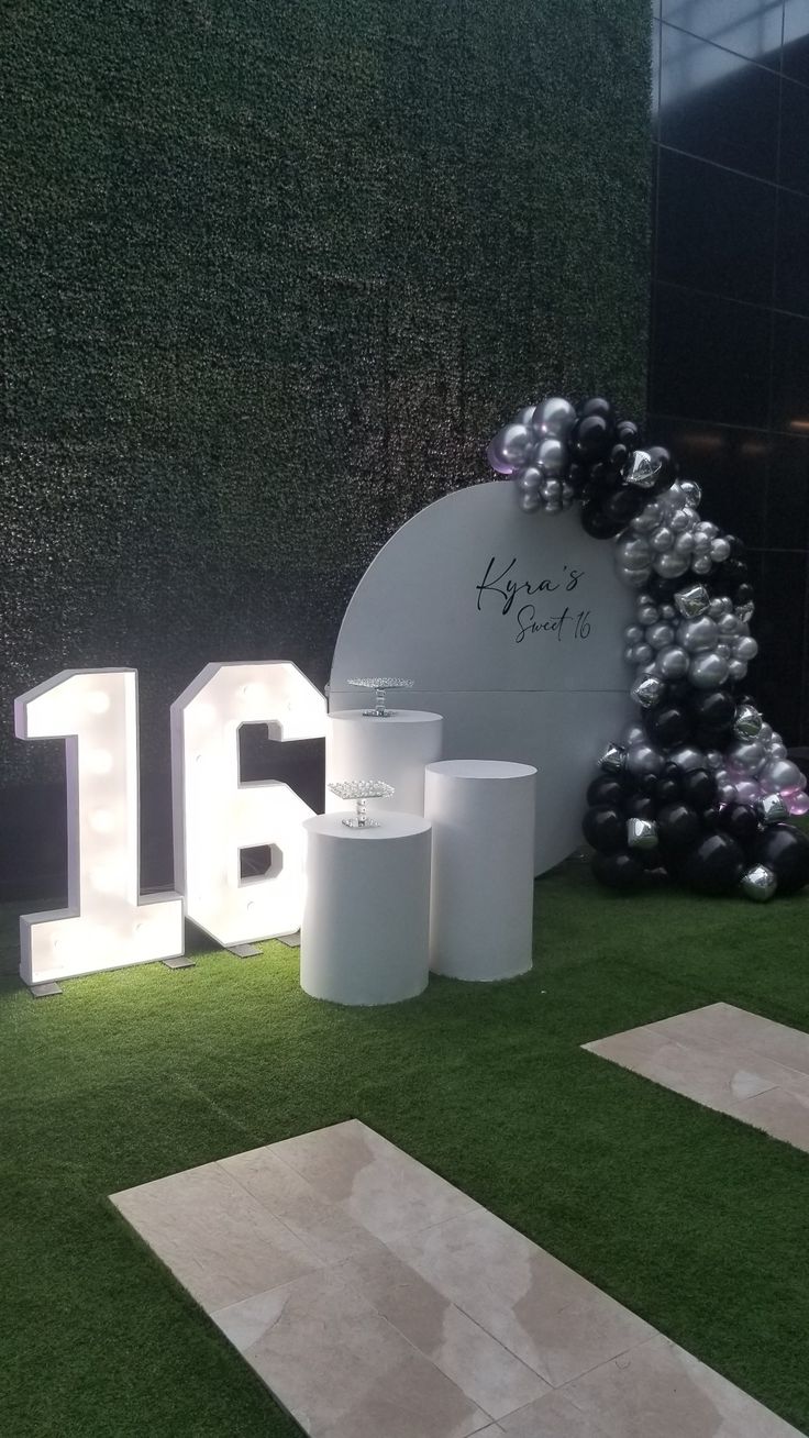 an artificial grass area with white and black balloons in the shape of numbers on it