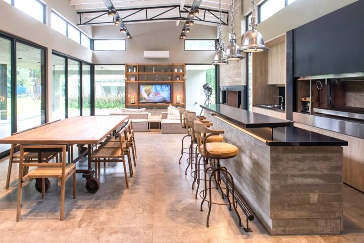 a large open kitchen and dining area with lots of counter space, bar stools and chairs