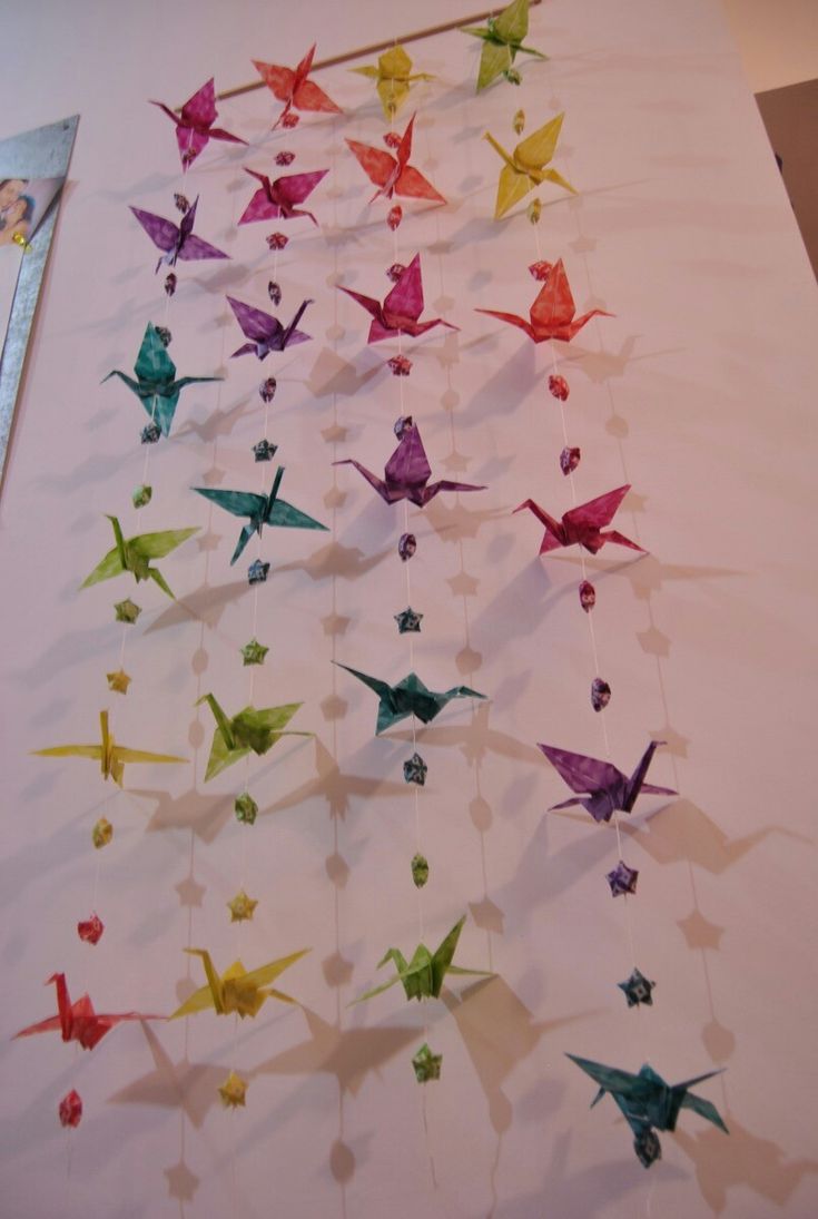 there are many origami birds hanging on the wall