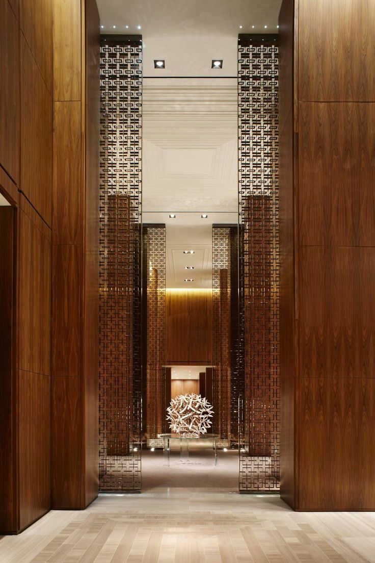 the hallway is lined with tall wooden columns and decorative wall paneling on either side