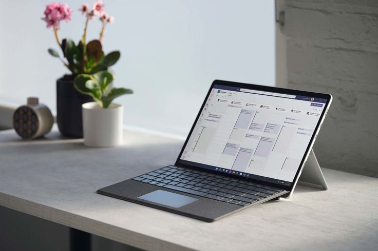 an open laptop computer sitting on top of a white table next to a potted plant