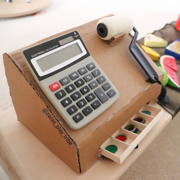 a calculator sitting on top of a cardboard box filled with crafting supplies