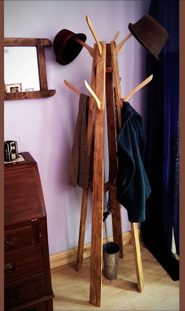 a coat rack with hats and scarves on it in front of a purple wall