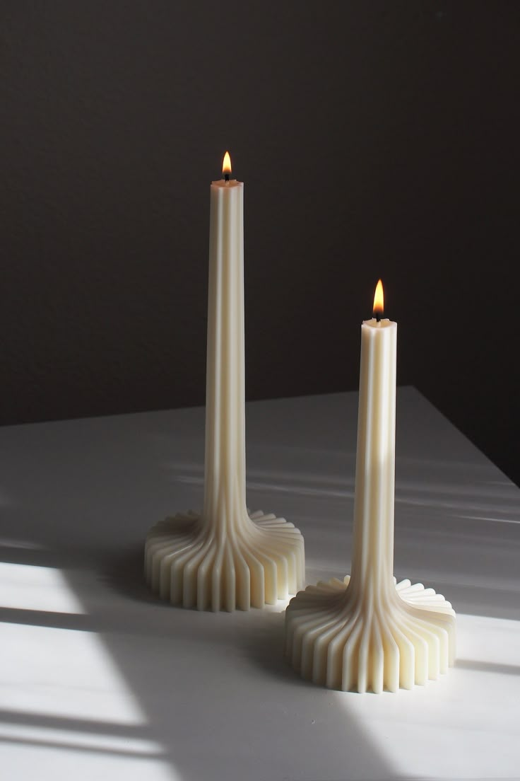 two white candles sitting next to each other on a table