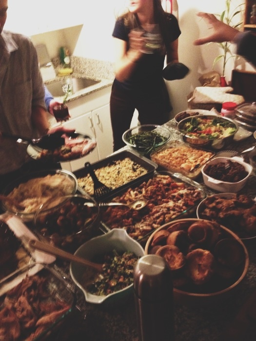 several people standing around a table full of food