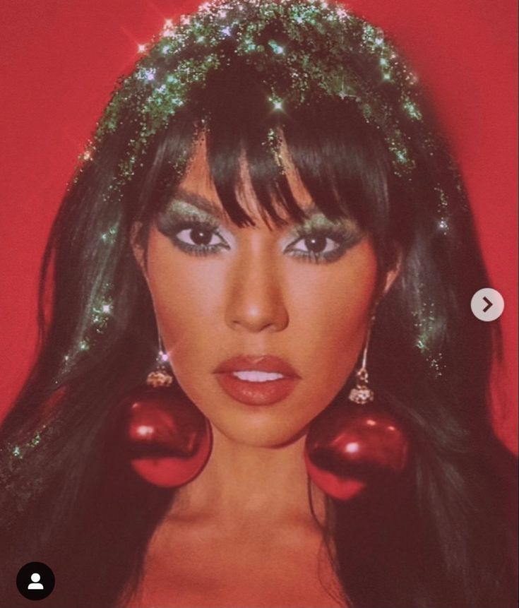 a woman with long black hair and green eyeshades wearing christmas decorations on her head