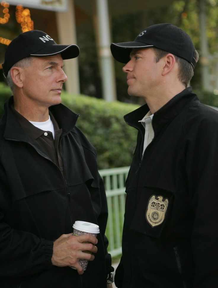 two men standing next to each other with coffee in their hands and one holding a cup