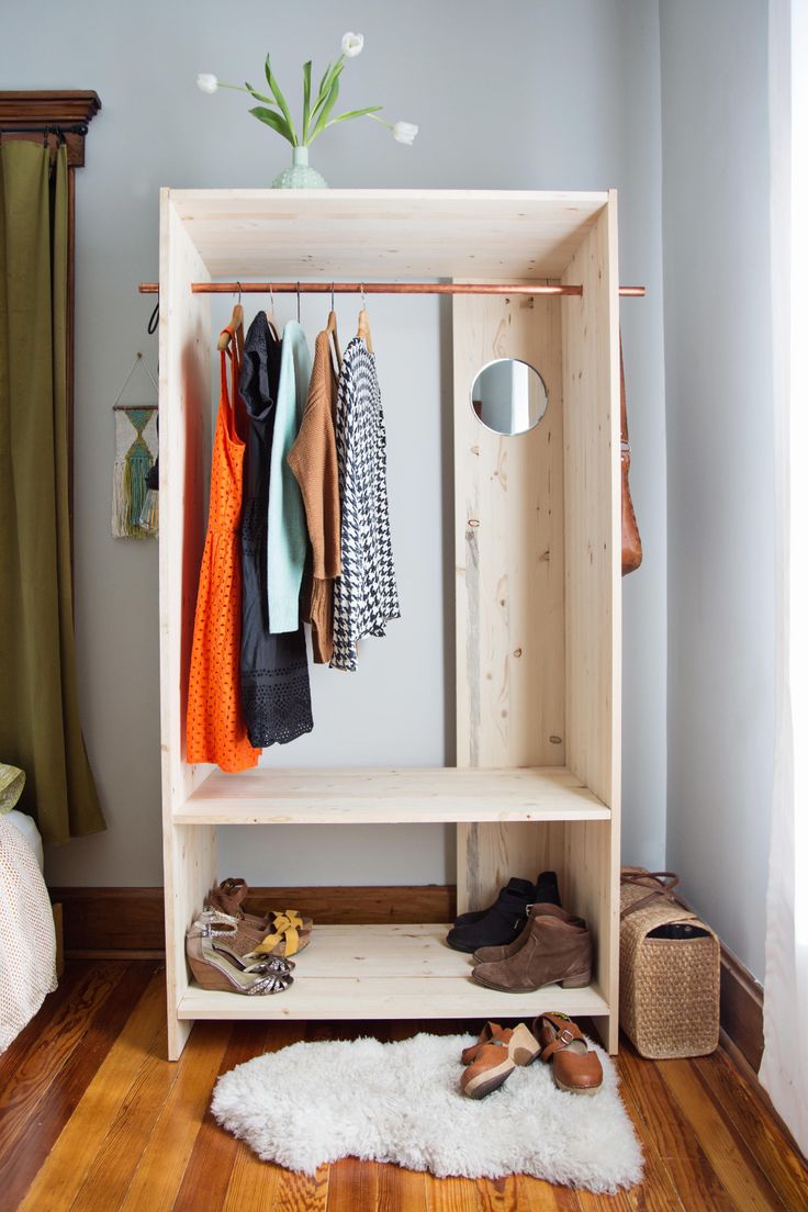 a wooden shelf with shoes and clothes hanging on it in a bedroom next to a bed