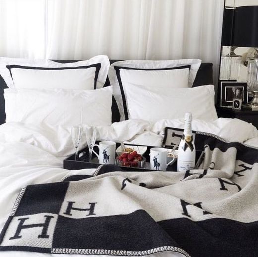 a black and white bed with pillows, blankets and pictures on it