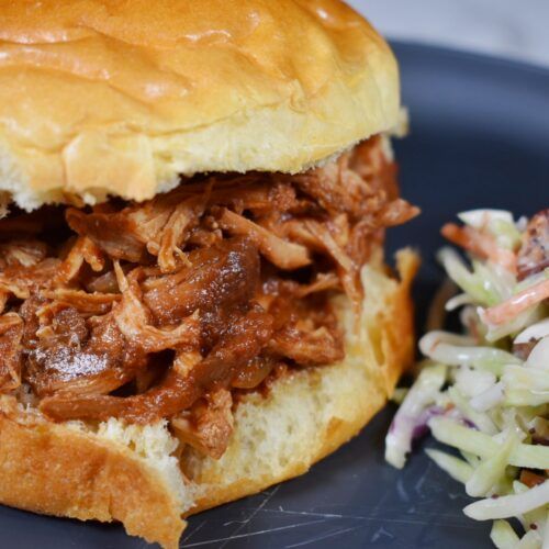 a pulled pork sandwich and coleslaw salad on a plate