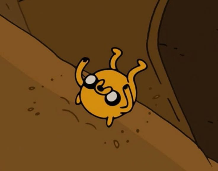 an orange cartoon character with big eyes on a brown surface in the middle of a cave