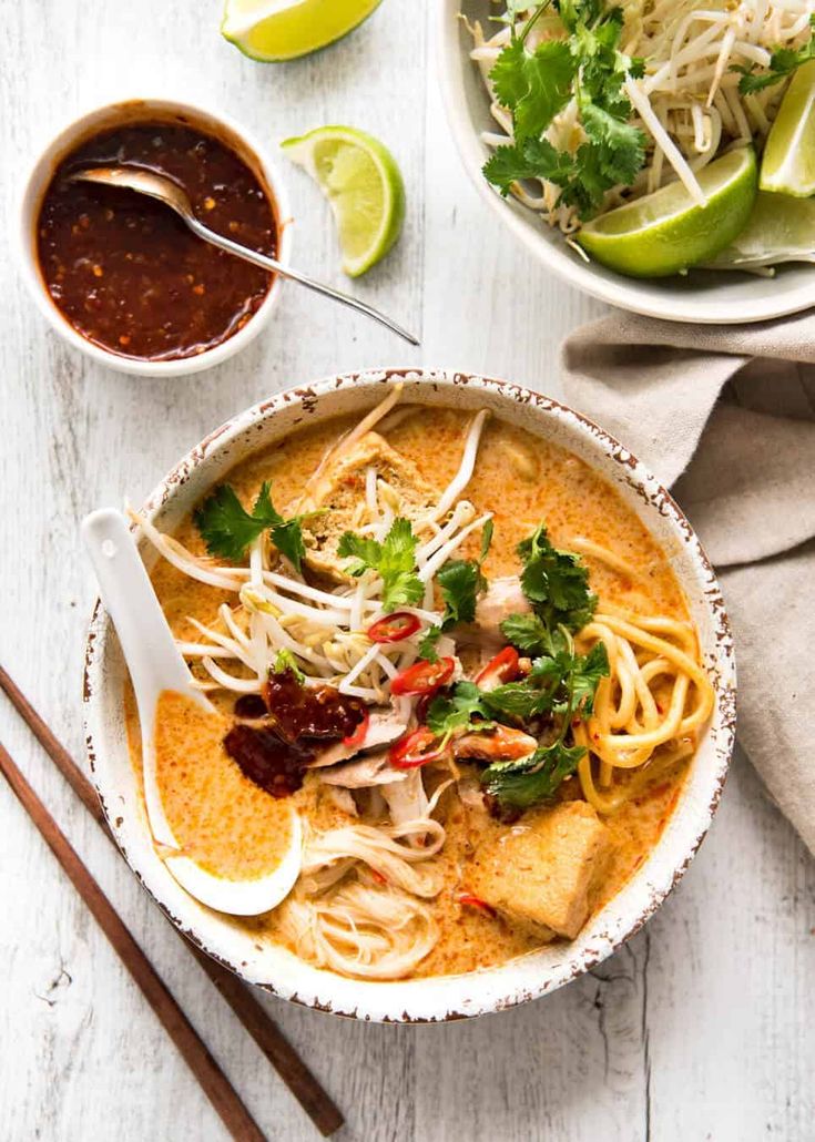 an overhead view of a bowl of soup with noodles and garnishes on the side