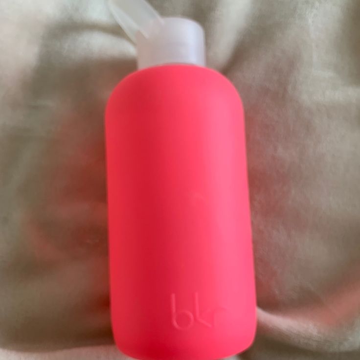 a pink water bottle sitting on top of a bed