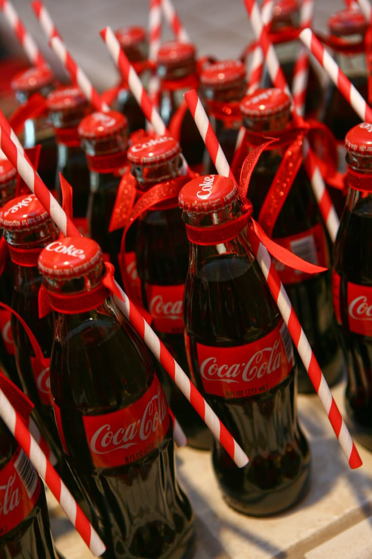 coca - cola bottles are lined up with red and white striped straws on them