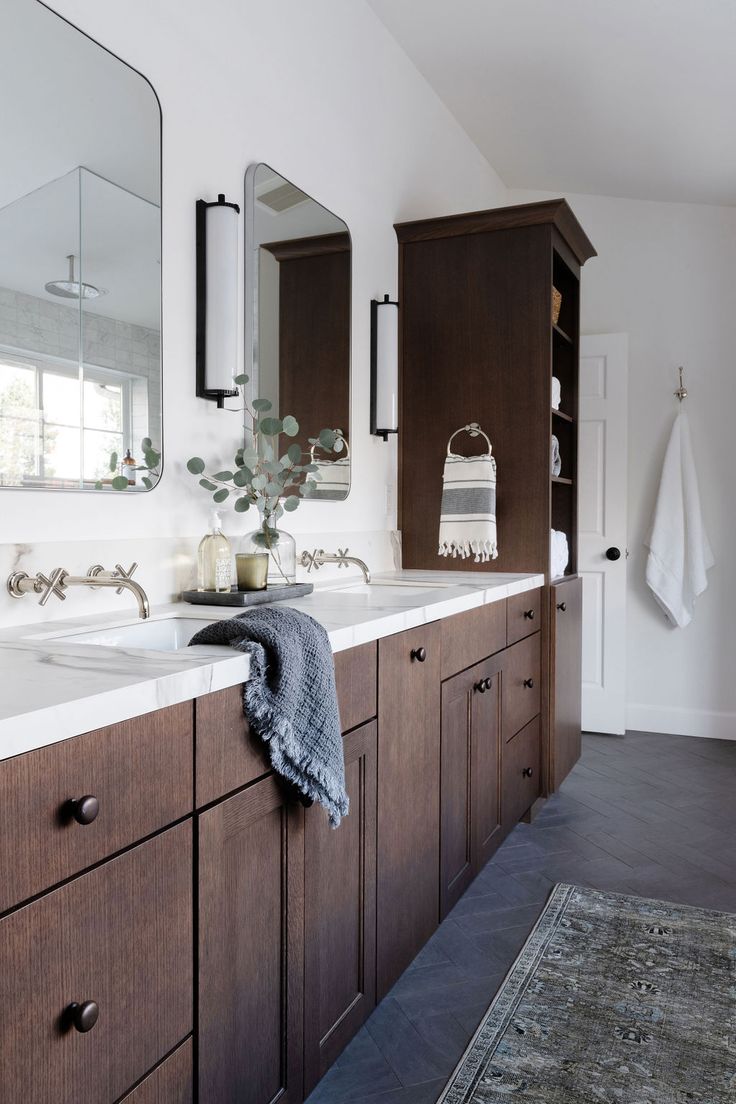 a bathroom with two sinks, mirrors and towels on the counter top in front of it