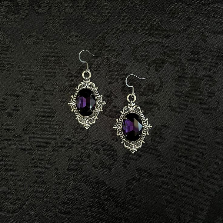 "These richly detailed earrings are made with antiqued silver tone settings. Their captivating design is accented with dark amethyst purple glass jewels.  Earrings measure 2\" in length (including stainless steel hooks) and 1\" wide.  Matching chokers are listed separately in our store. If you don't see items with a color you want, feel free to ask about availability."