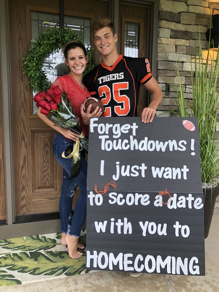 a man and woman standing next to a sign that says forgets for touchdowns i just want to score a date with you to home coming