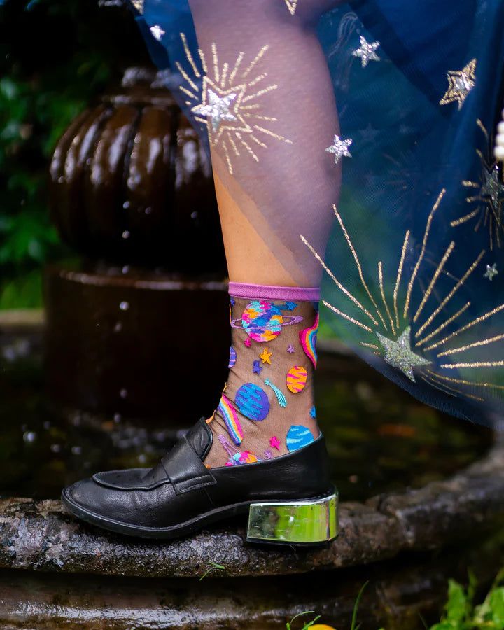 Calling all space babes!! Inspired by pop art, the funky planets print sheer sock features a variety of psychedelic planets, wavy rainbows, and shooting stars set against black sheer fabric. Bold, saturated colors give this sock a festival vibe and ensures your outfit makes a statement. Reinforced with a purple cuff and toe and and blue heel for the ultimate celestial themed accessory. Shop more fabulously fun socks from Sock Candy here! One Size. Recommended fit US W5.5-10. 200 Needle Count. 54% Nylon, 45% Combed Cotton, 1% Lycra Machine wash cold inside out with like colors - or hand wash if you want to be really safe. Hang dry. Do not tumble dry. Do not bleach. Do not iron. Photos courtesy of Sock Candy Midnight Era, Sock Candy, Black Sheer Fabric, Aesthetic Socks, Fancy Socks, Dita Von Teese Lingerie, Maximalist Fashion, Sheer Socks, 30s Fashion