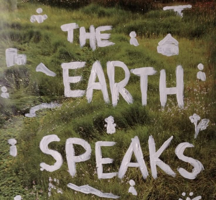 the earth speaks written in white paint on green grass