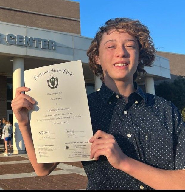 a young man holding up a certificate in front of a building