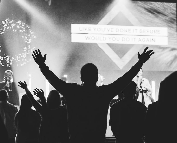 a man standing in front of a crowd with his arms up and hands raised to the side