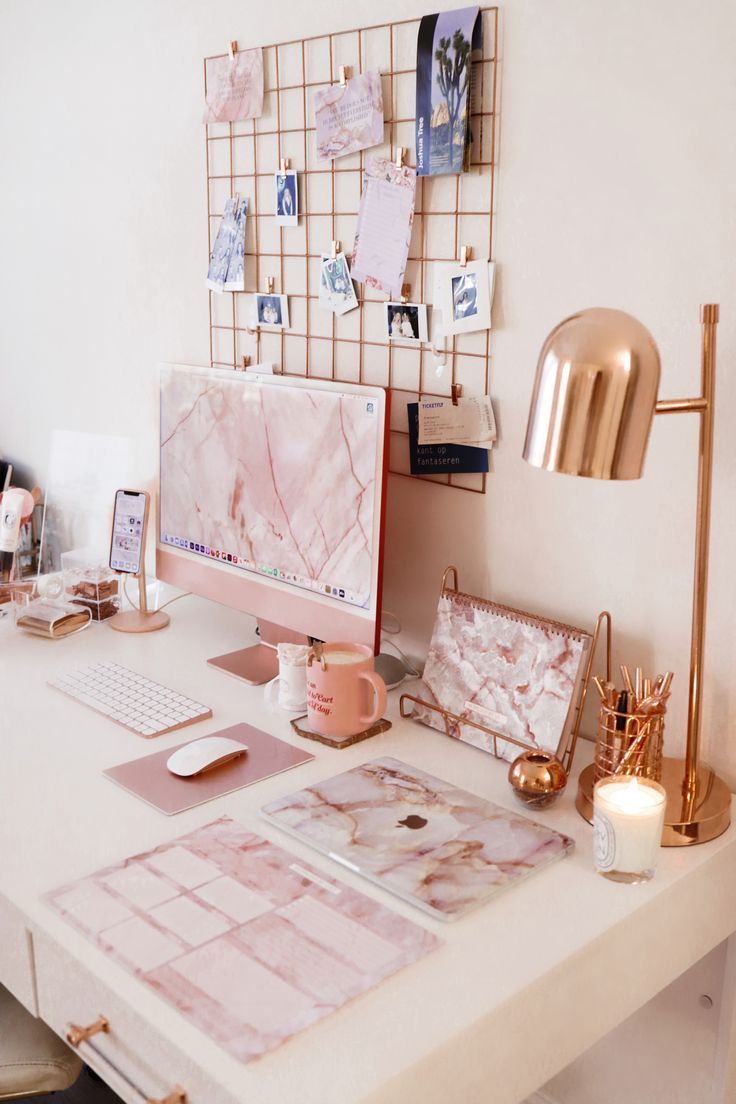 a white desk topped with a computer monitor next to a gold lamp and other items