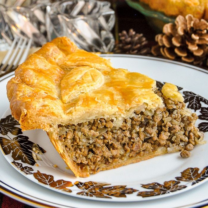 a piece of pie sitting on top of a white and black plate next to pine cones