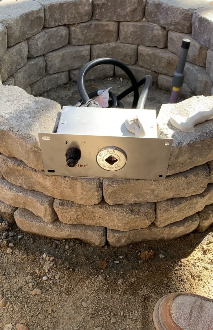 an outdoor fire pit made out of rocks and bricks with a steering wheel on top