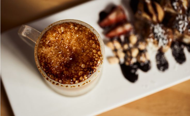 there is a cup of coffee and some pastries on the plate