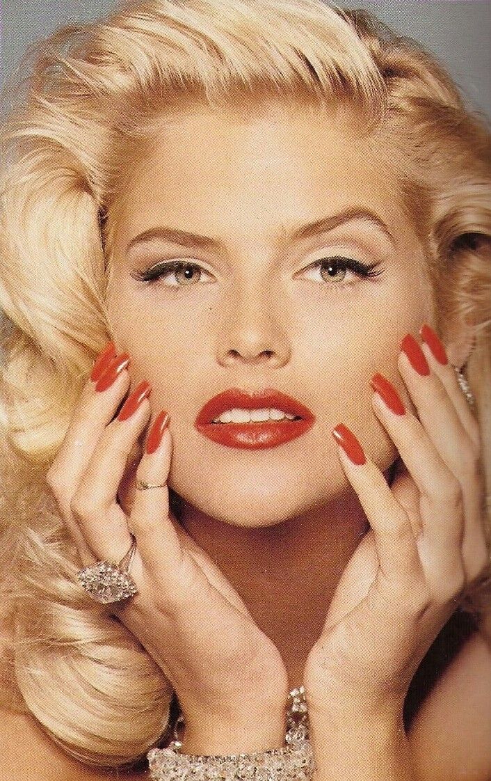 a woman with blonde hair and red nail polish holding her hands to her face while posing for the camera