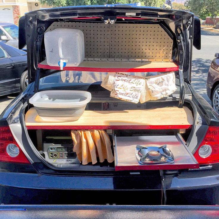 the back end of a car with its trunk open and food in it's trays