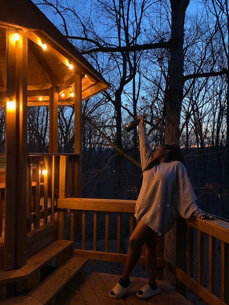 a woman is standing on the porch with her arms in the air and looking up