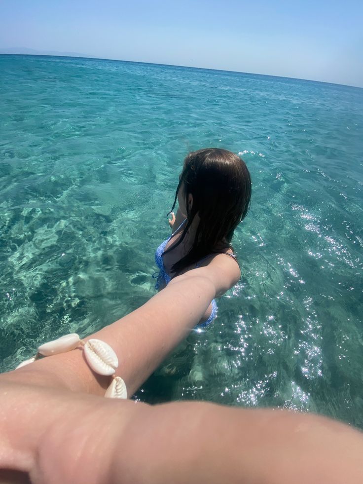 a woman swimming in the ocean with her arm wrapped around another person's wrist