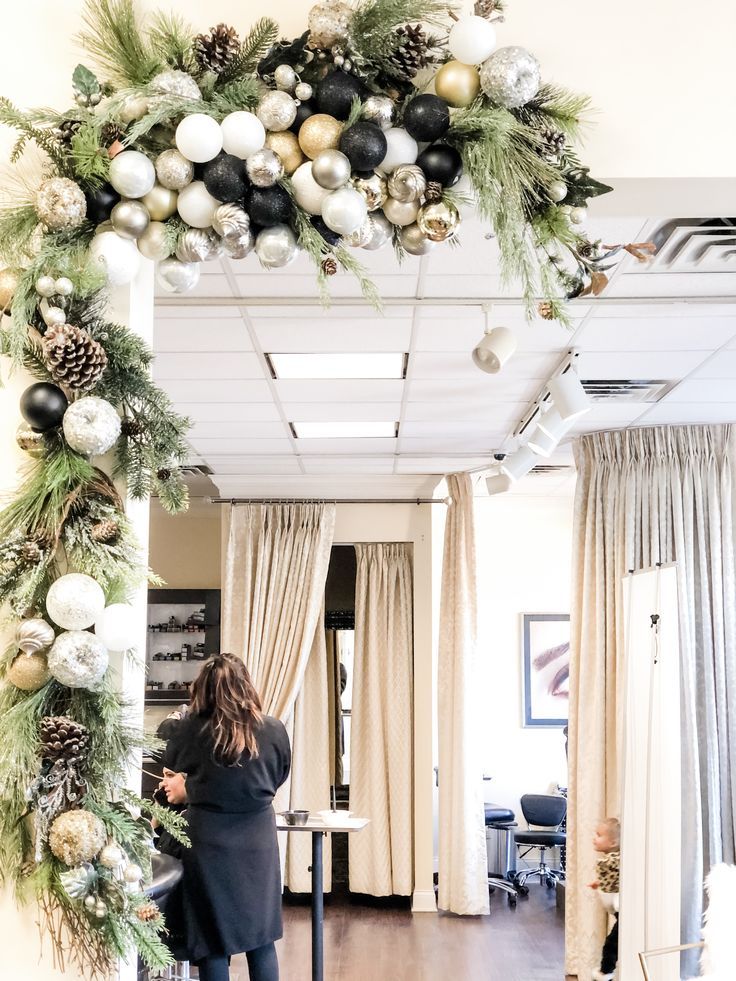 a woman standing in front of a mirror with christmas decorations hanging from it's ceiling