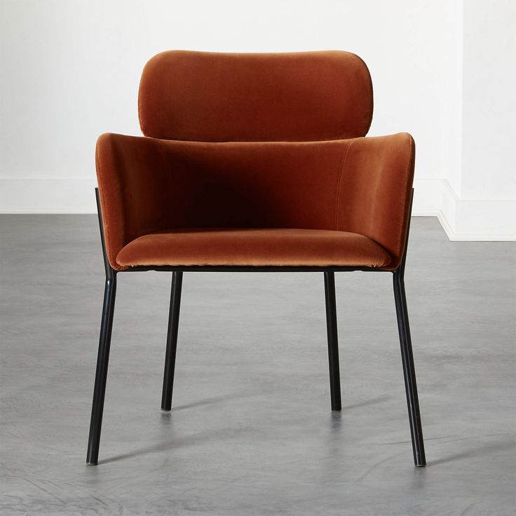 an orange chair sitting on top of a floor next to a white wall and black legs