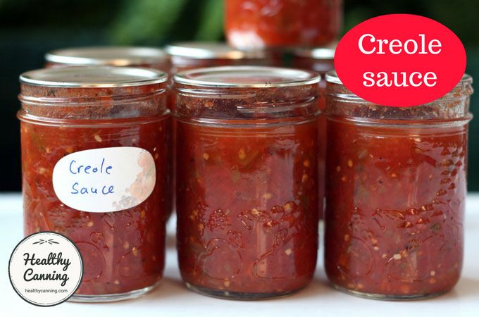 four jars filled with red sauce sitting on top of a table