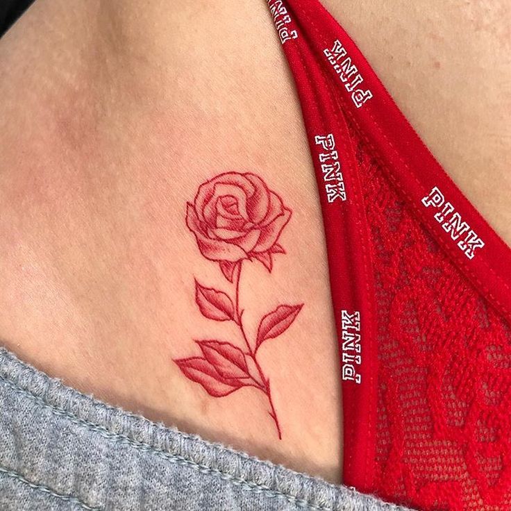 a woman's stomach with a rose tattoo on it