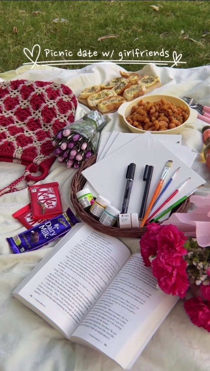 an open book sitting on top of a white blanket next to flowers and other items