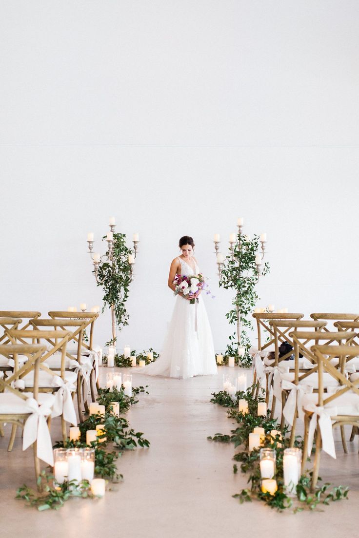 a bride and groom standing in front of rows of chairs with greenery on them