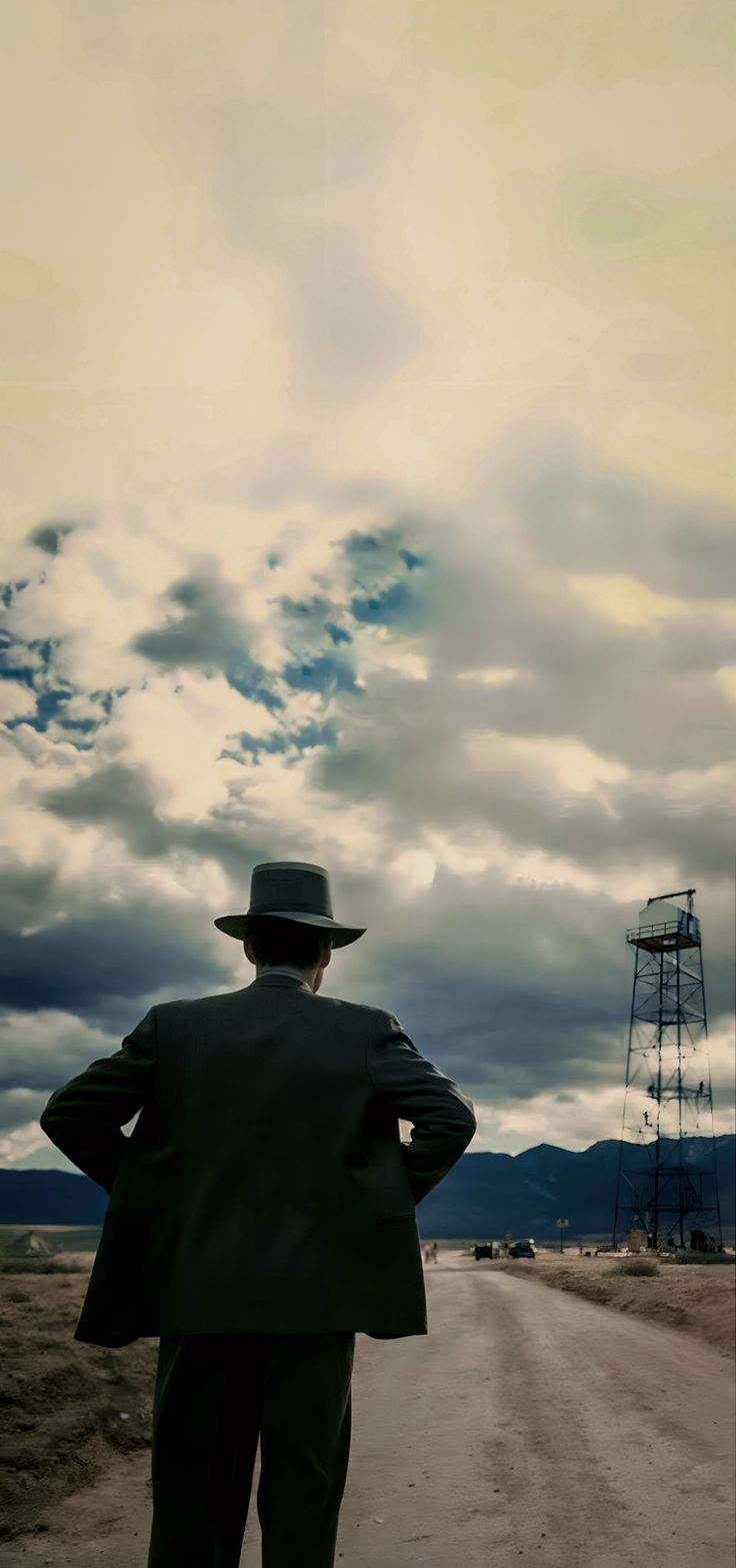 a man in a suit and hat standing on a dirt road looking at the sky