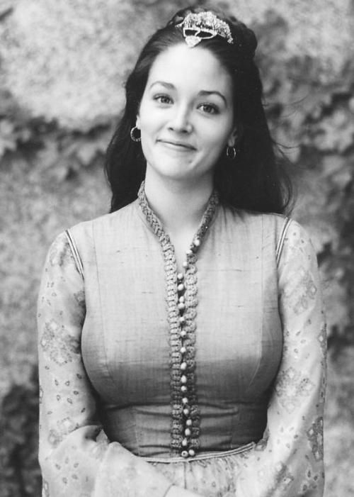 black and white photograph of a woman wearing a long sleeved dress with beads around her neck