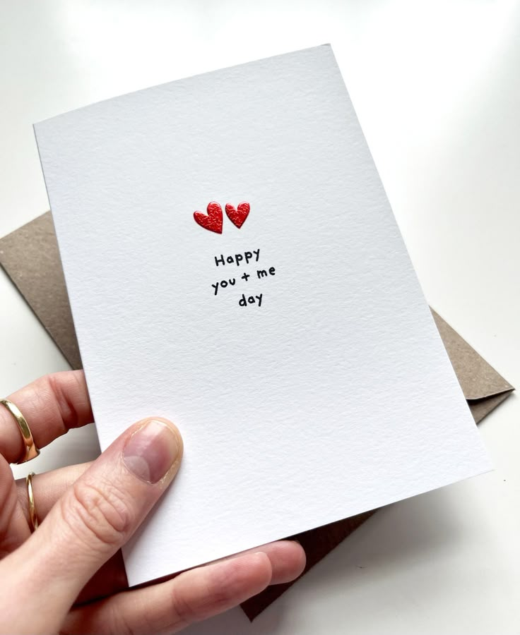 a hand holding a card with the words happy you + me day written on it