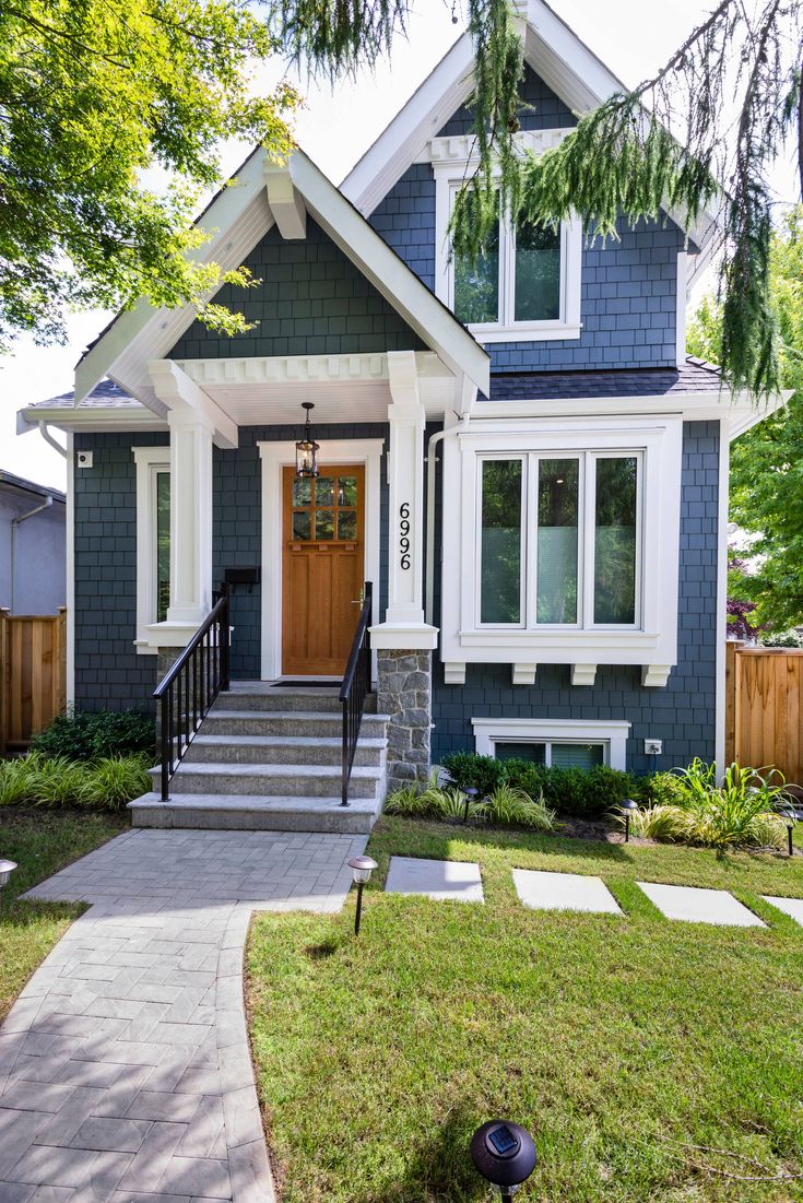 a house with blue siding and white trim on the front door is shown in this suburban neighborhood